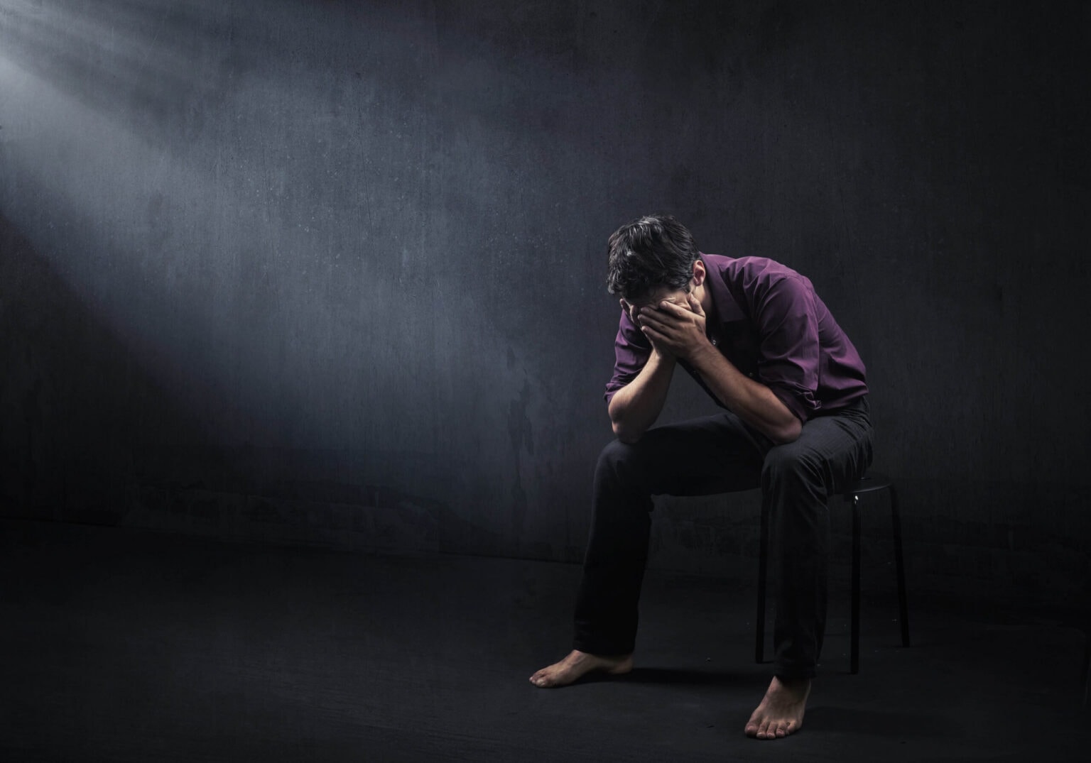 man with depression in a dark room